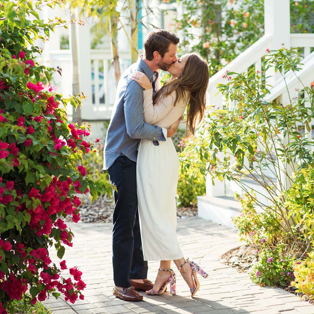 Portrait of a couple kissing amid flowers by Kristina Wikle